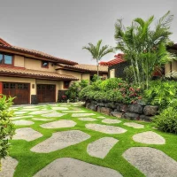 A beautifully landscaped home with a stone pathway, surrounded by tropical plants and greenery.